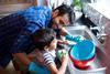 Man helping his son wash up at kitchen sink