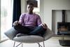 Man sat in lotus position on chair with eyes closed