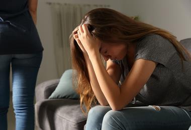 teenage girl sitting on sofa with head in her hands