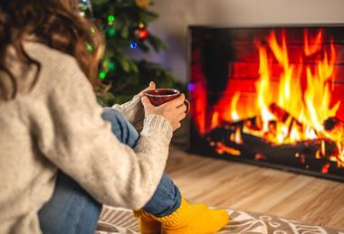 Woman sat cozily in from of a sitting room fire