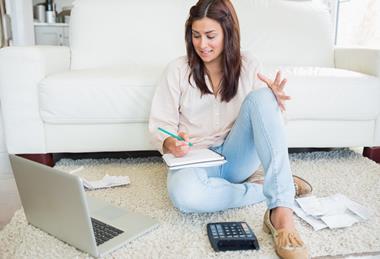 Woman sitting in her lounge with laptop and calculator