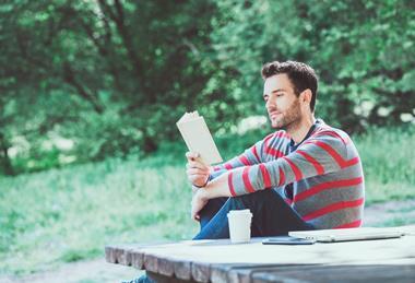 Young man reading a book in the countryside