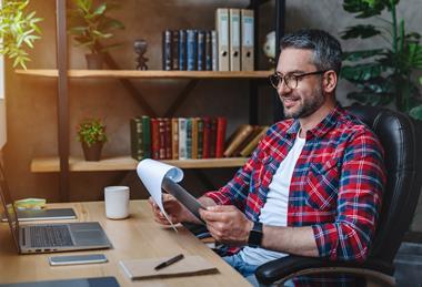 Middle aged man making notes on a pad looking happy