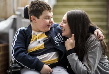 Mother cuddling son in wheelchair