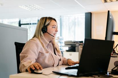 woman sat at computer with a headset on