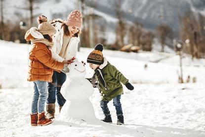 Family making a snowman laughing and having fun