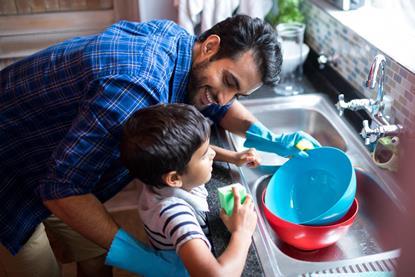 Man helping his son wash up at kitchen sink