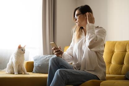 Woman looking at her phone in her home with cat sat next to her