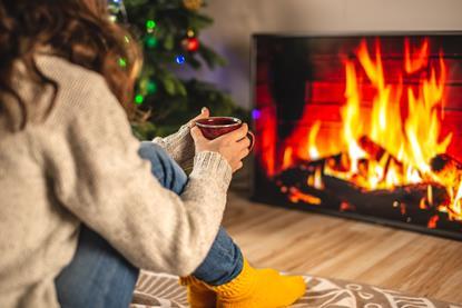 Woman sat cozily in from of a sitting room fire