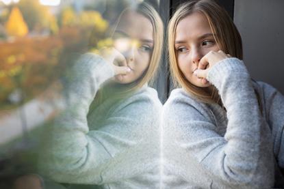 Girl sitting by a window staring outside