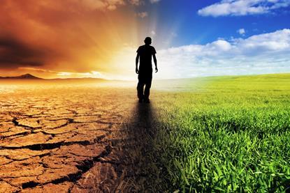 Man walking towards a beautiful sunset along a straight path with barren land on his left and lush land on his right