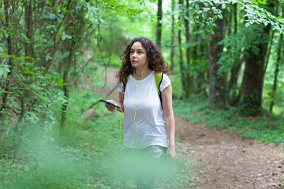 Young woman walking in the woods listening to music
