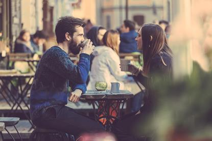 Man and woman drinking coffee in street cafe