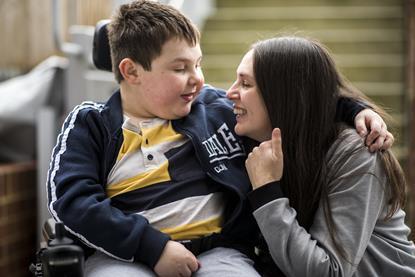 Mother cuddling son in wheelchair