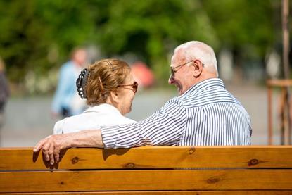 Older couple sitting on a bench laughing