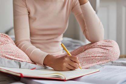 Woman sat on her bed writing in diary