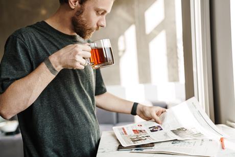 Man drinking a cup of tea and reading a newspaper