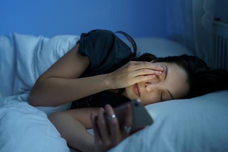 Women lying in bed looking at her phone