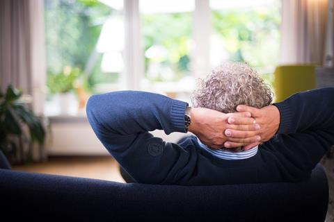 Back image of a man relaxing on sofa looking out a window