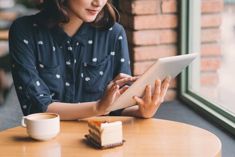 Lady sat at a coffee table using tablet